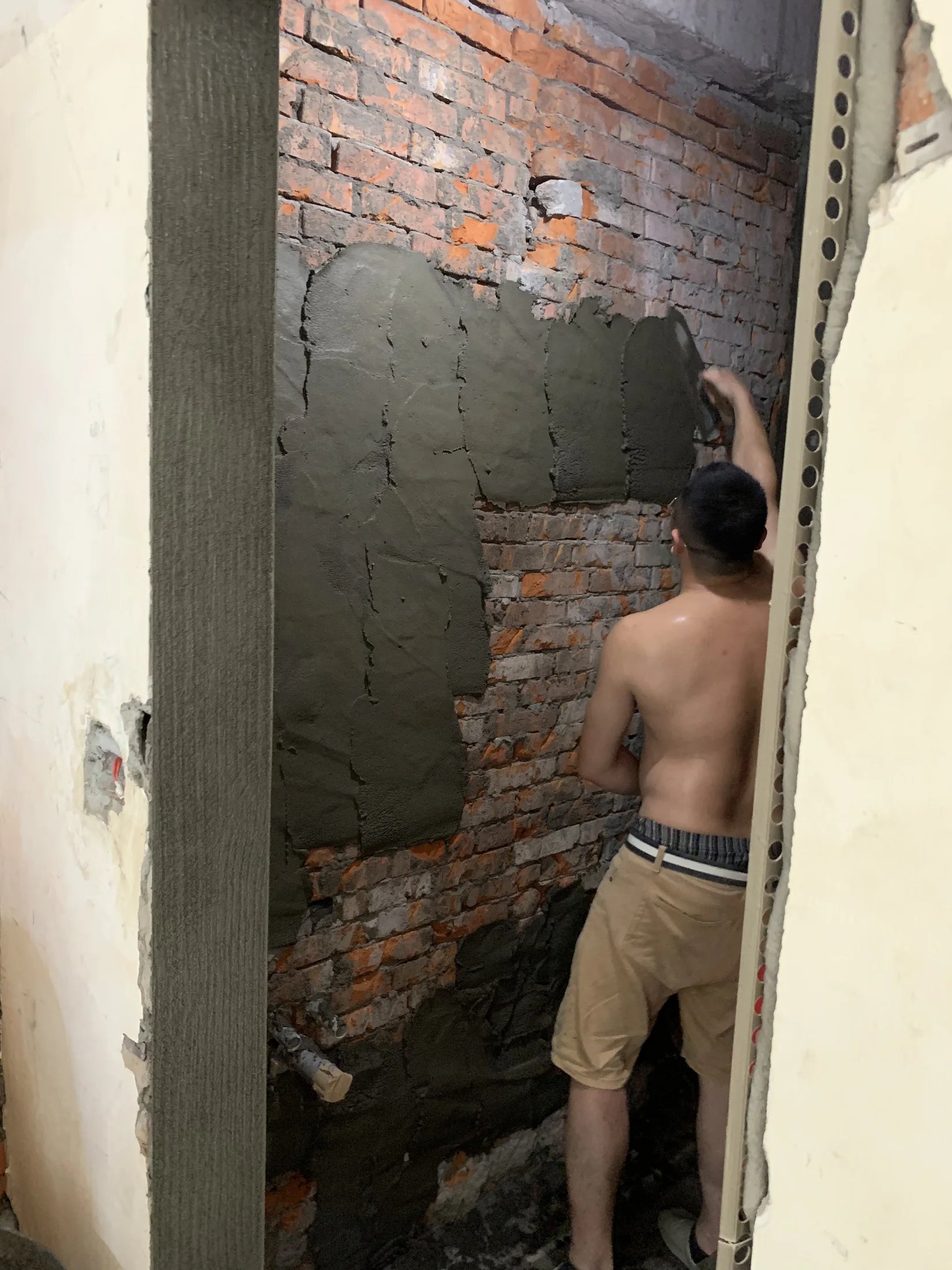 泥作人員在紅磚牆面分區抹上水泥砂漿