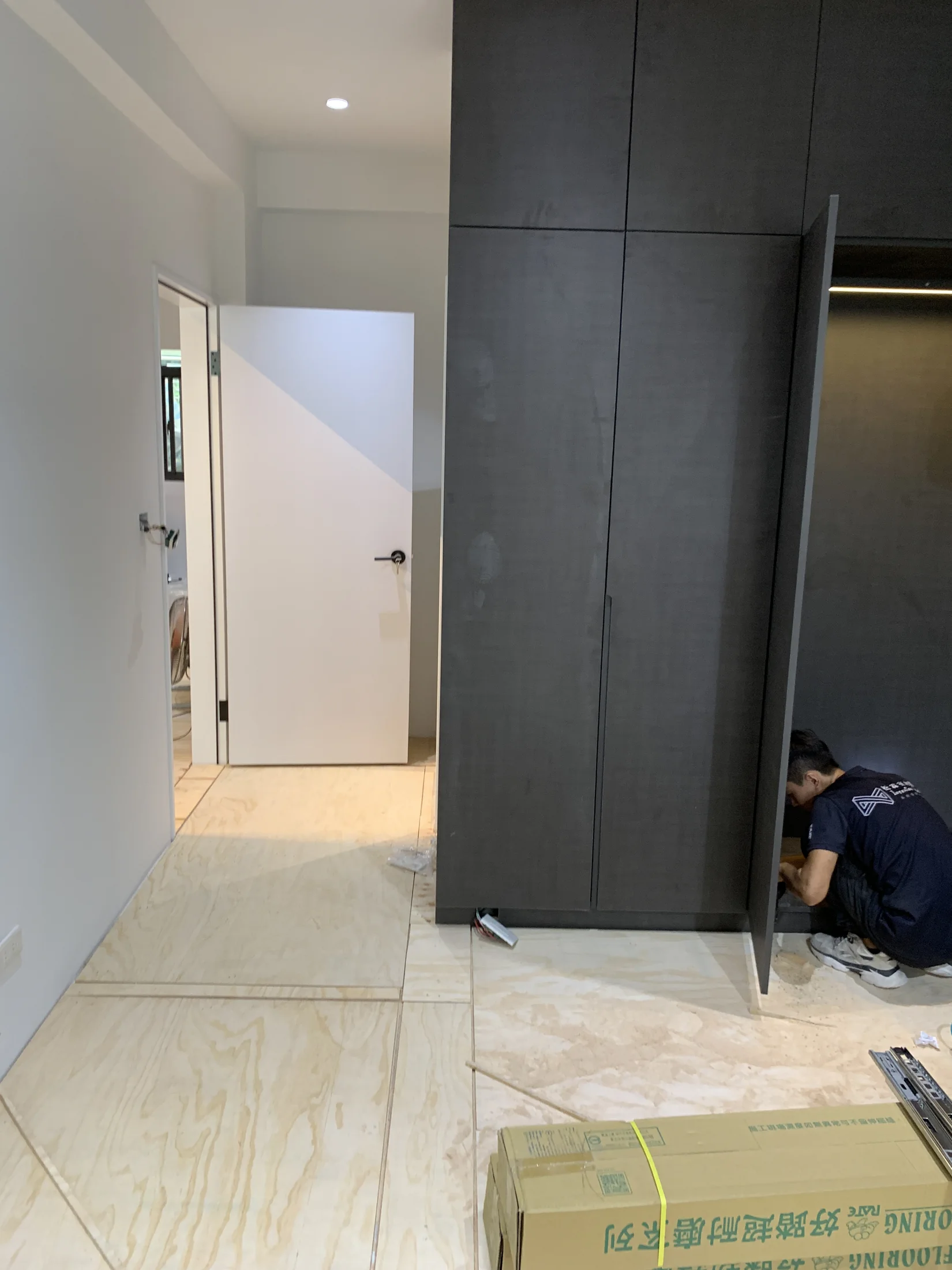 房間入口與深色櫃體旁正在鋪設木地板